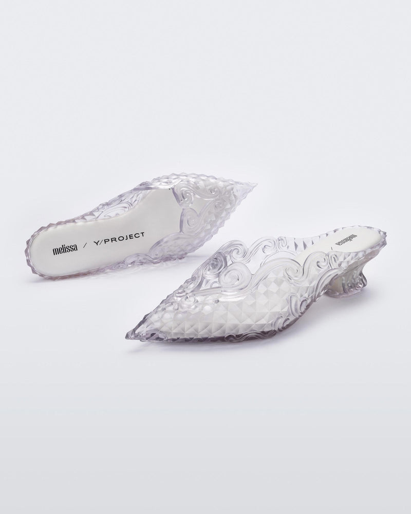 An angled front and top view of a pair of clear white Melissa Court heels with a heart detail on the front and a checkered pattern texture.