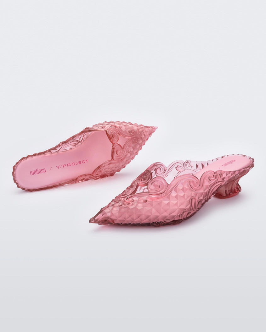 An angled front and top view of a pair of clear pink Melissa Court heels with a heart detail on the front and a checkered pattern texture.