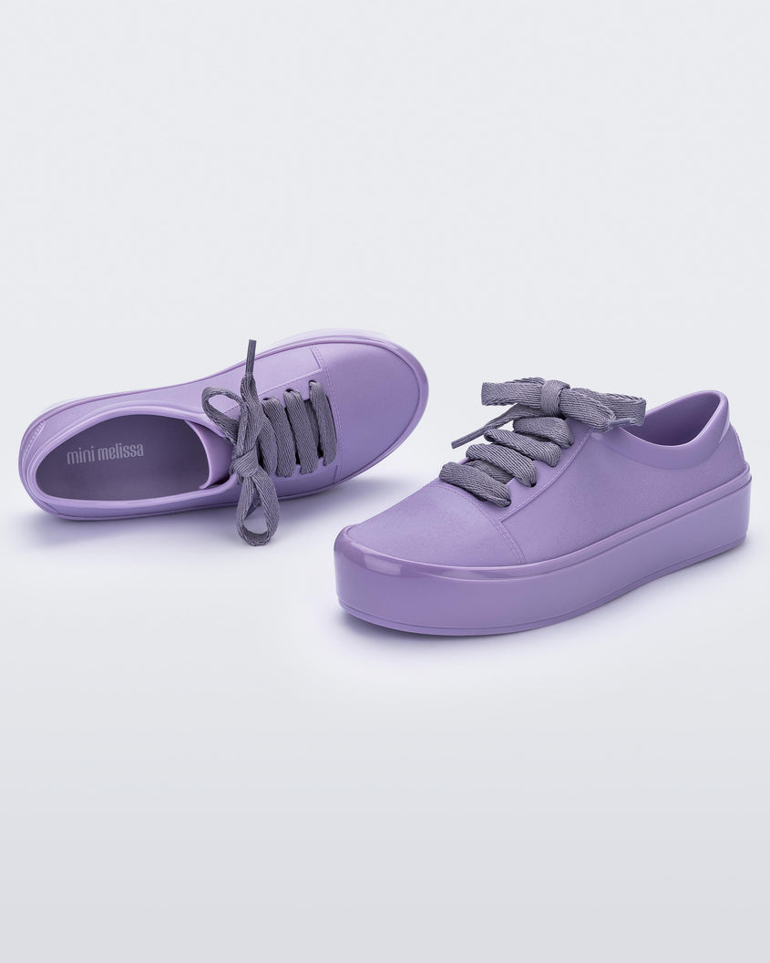 An angled side and top view of a pair of lilac Mini Melissa Street sneakers with a lilac base and laces.