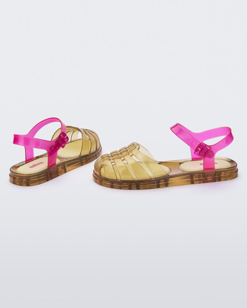 Angled view of a pair of transparent yellow and pink Melissa Obsessed sandals.