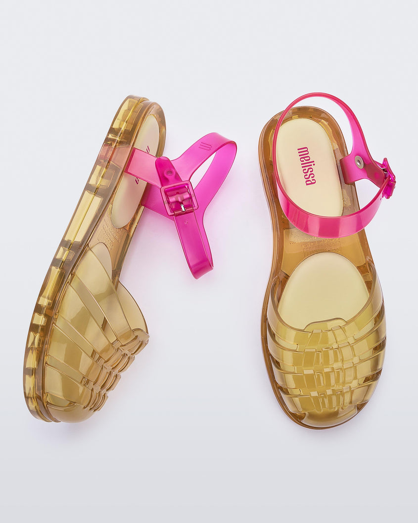 Top and side view of a pair of transparent yellow and pink Melissa Obsessed sandals.