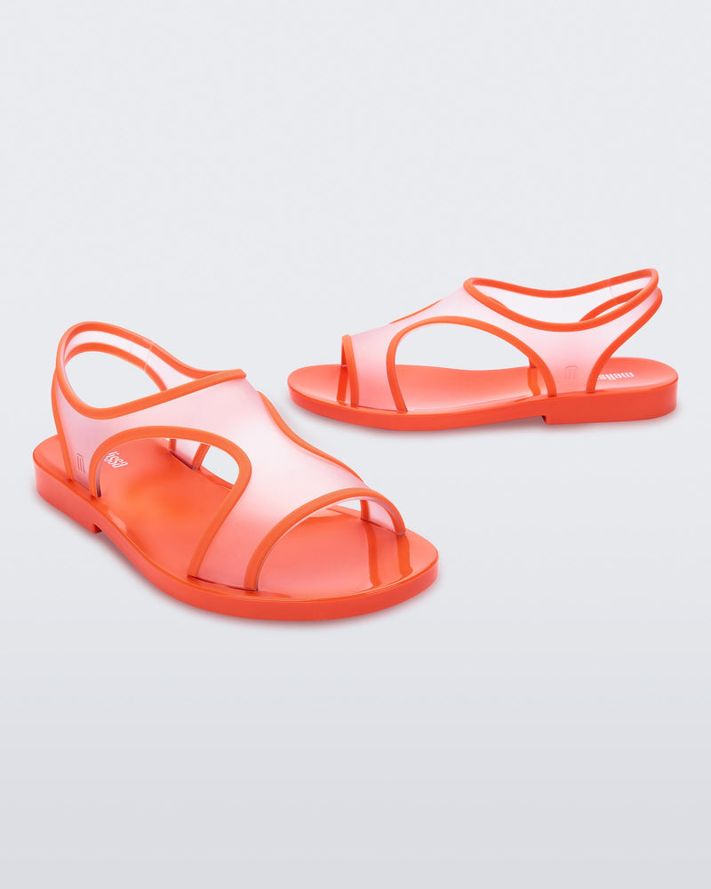 An angled front and side view of a pair of transparent orange Melissa Bikini Sandal with two transparent orange straps conjoining in the middle and an orange insole.