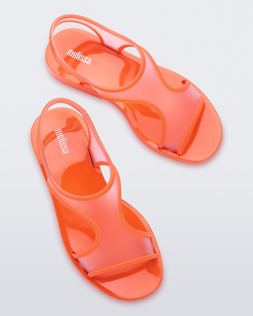 Top view of a pair of transparent orange Melissa Bikini Sandal with two transparent orange straps conjoining in the middle and an orange insole.
