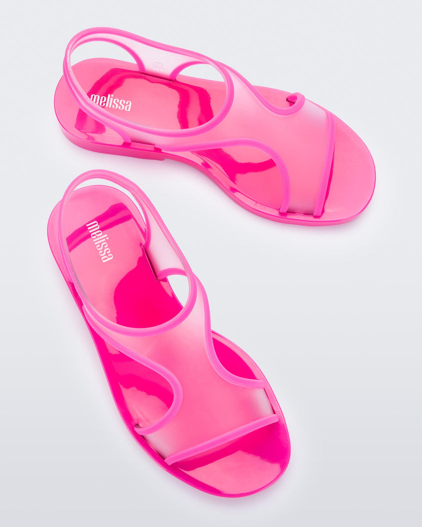 Top view of a pair of transparent neon pink Melissa Bikini Sandals with two transparent pink straps conjoining in the middle and a pink insole.