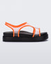 Side view of a black/orange Melissa Bikini Platform sandal with two transparent orange straps conjoining in the middle and a black sole.