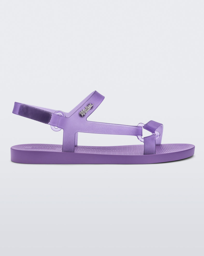 Side view of a Melissa Sun Downtown sandal with transparent lilac front cross and back ankle straps and a lilac purple sole. 