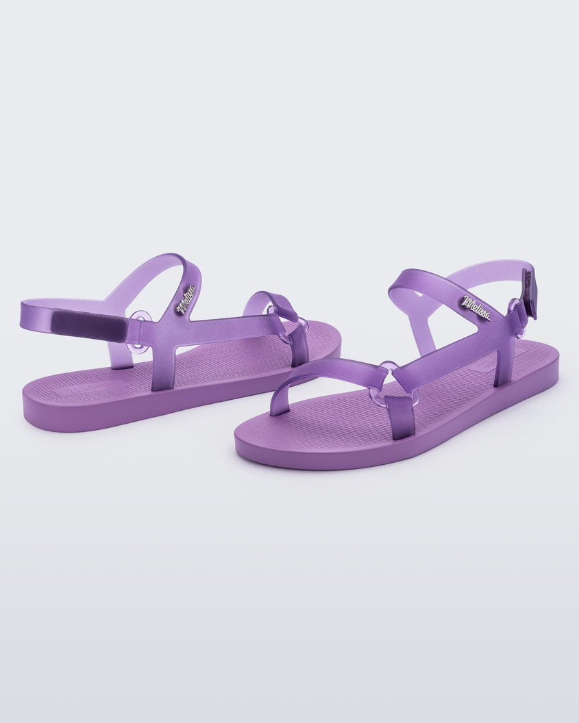 Angled view of a pair of Melissa Sun Downtown sandals with transparent lilac front cross and back ankle straps and a lilac purple sole. 