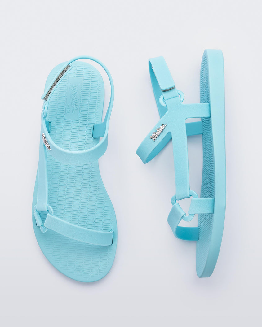 Top and side view of a pair of Melissa Sun Downtown sandals with light blue front cross and back ankle straps.