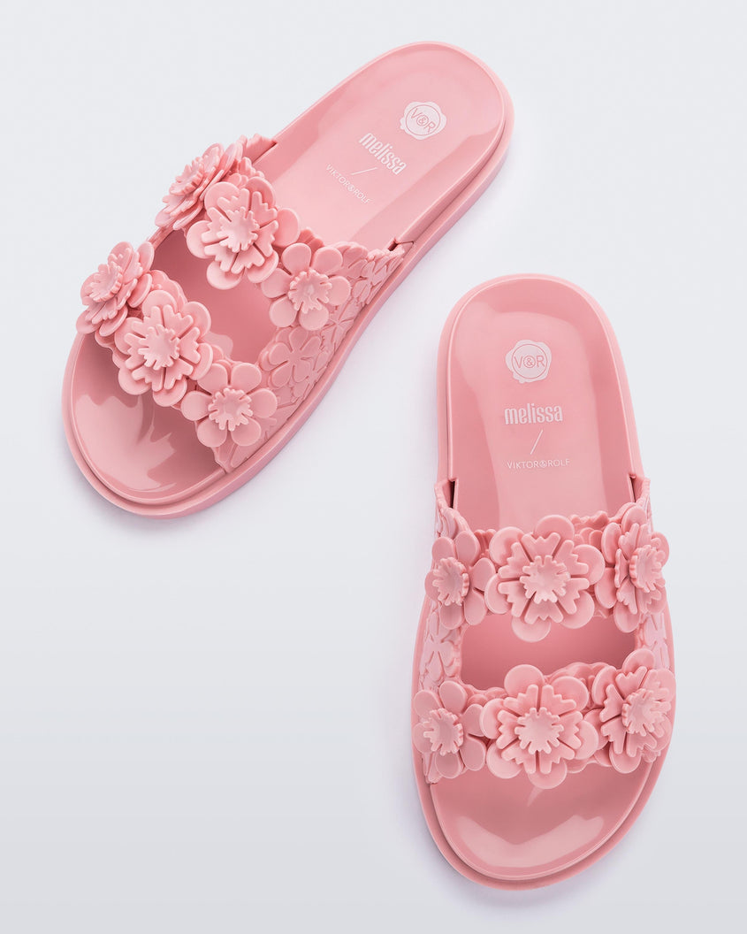 Top view of a pair of Melissa Wide Blossom Slides in pink with double floral embossed buckle straps and 3D flower appliques