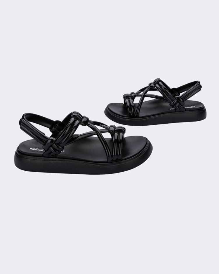 A side view of a pair of black Melissa Papete Essential sandals with straps.