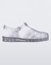 Side view of a glitter clear Melissa Possession sandal with several straps and a closed toe front.