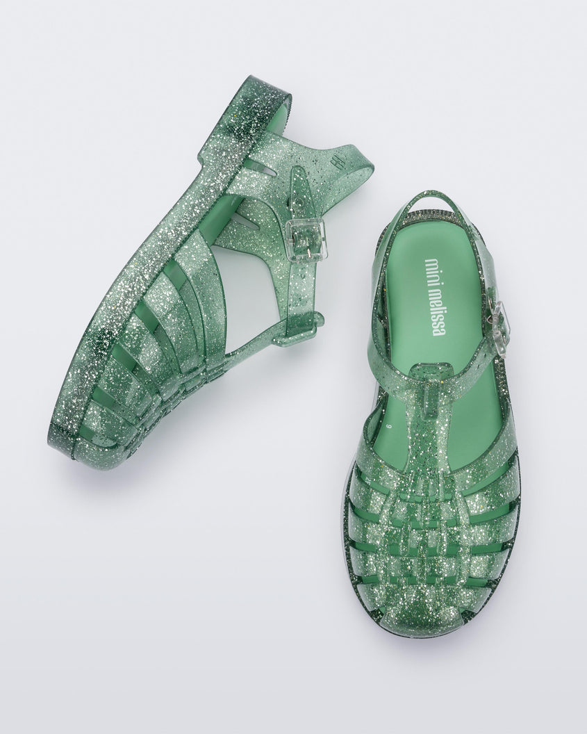 Top and side view of a pair of Green/Glitter/Silver Mini Melissa Possession sandals with several straps and a green glitter base.
