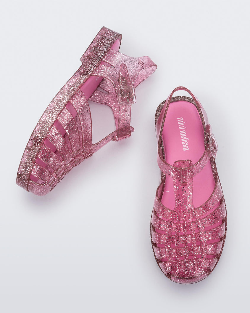 A top and side view of a pair Pink/Glitter/Silver Mini Melissa Possession Shiny sandals with several straps and a pink glitter base.
