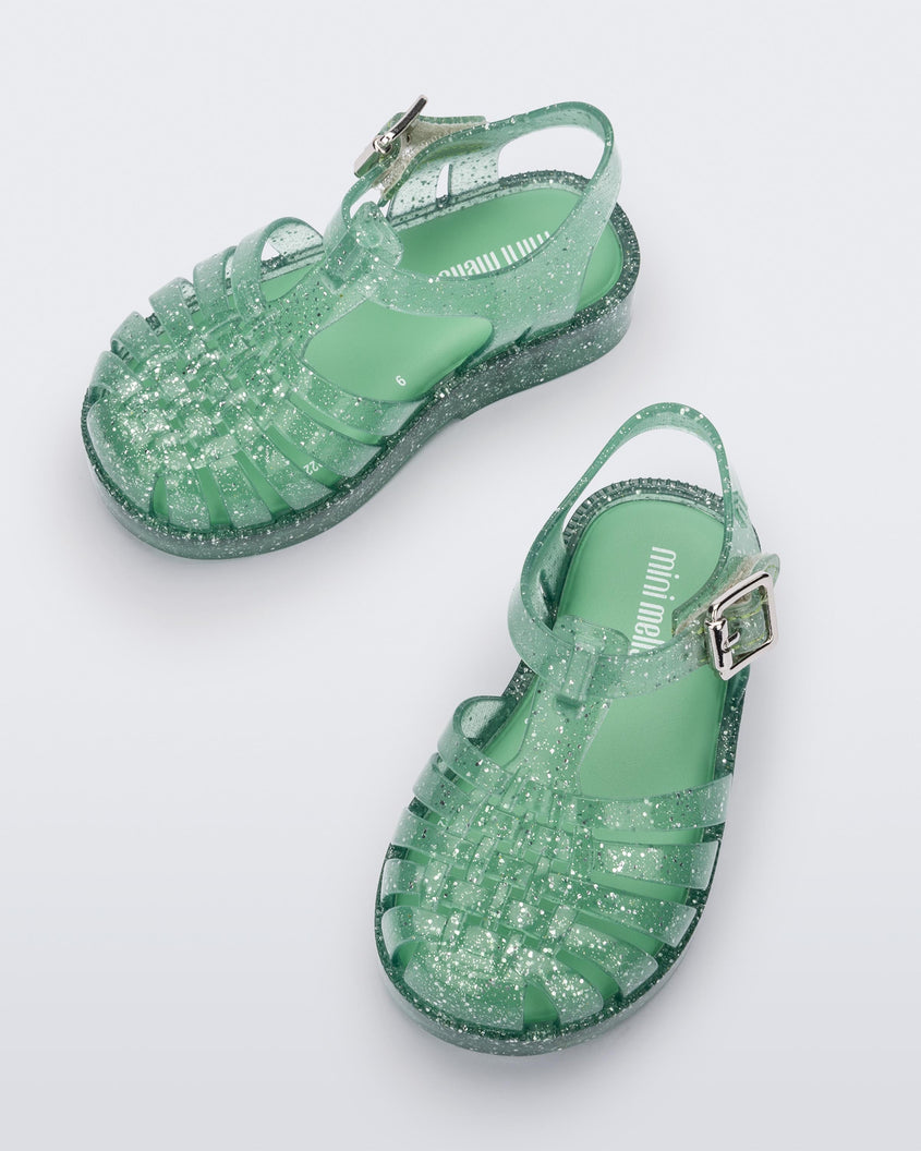 Top view of a pair of Green/Glitter/Silver Mini Melissa Possession Shiny sandals with several straps, closed toe front and an ankle strap.