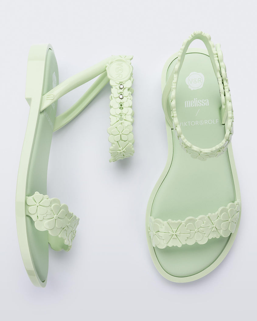 Top and side view of a pair of Melissa Wave Blossom sandals in Green with floral design ankle and front straps and double snap closure 