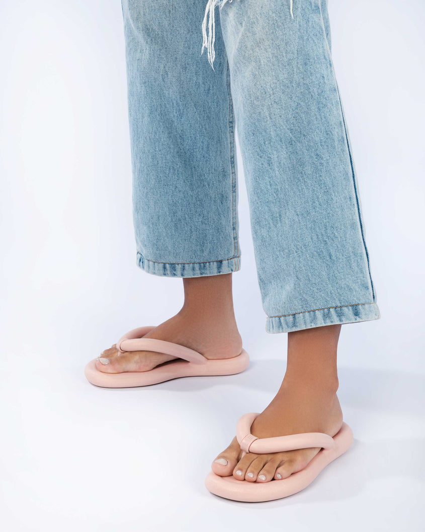 A model's legs wearing a pair of light pink Melissa Free Flip Flops with puffer-like straps.