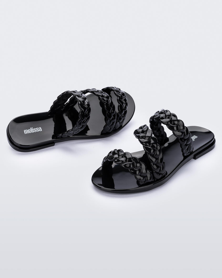 An angled front and side view of a pair of black Melissa Wrap slide with 3 braid like straps.