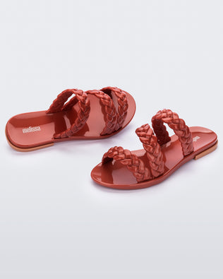 An angled front and top view of a pair of brown/beige Melissa Wrap slides with three braid like straps.