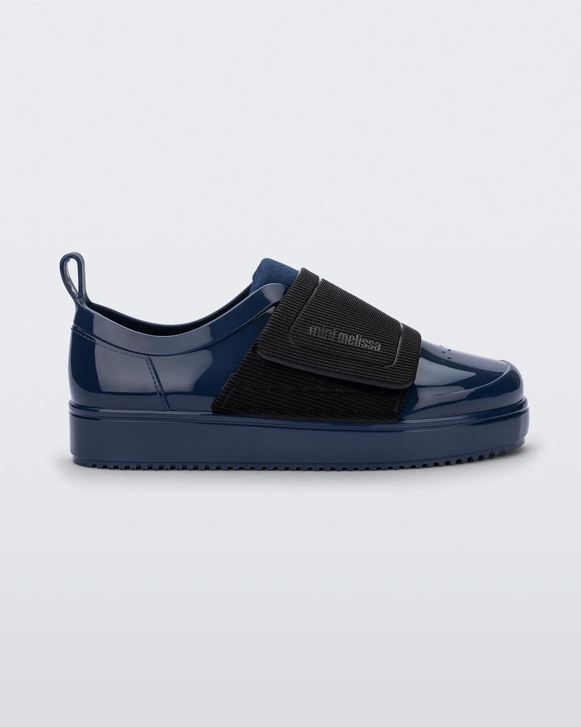Side view of a blue/black Mini Melissa Jelly Pop Sneaker with a blue base and a black velcro strap.