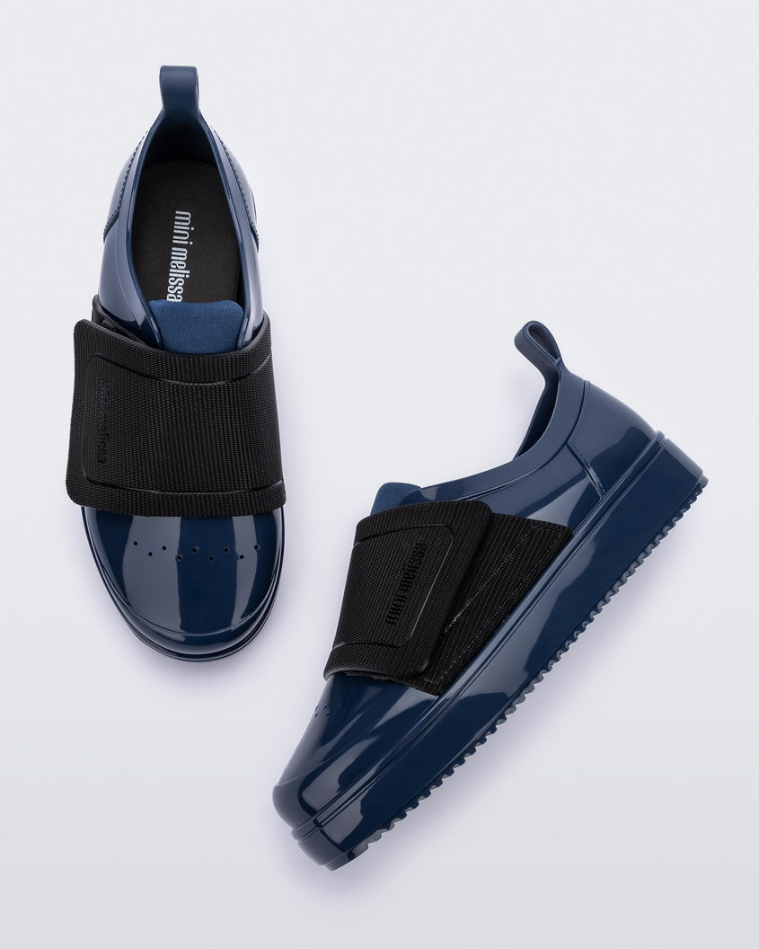 Top and angled view of a pair of blue/black Mini Melissa Jelly Pop Sneakers with a blue base and a black velcro strap.