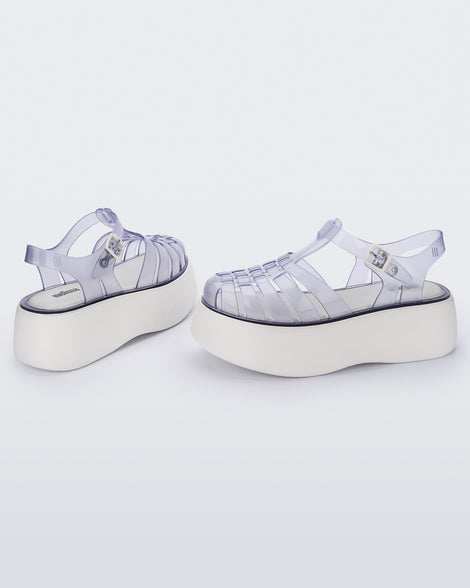 A side and back view of a pair of Clear/White Melissa Possession Platform sandals with several straps and a closed toe front.