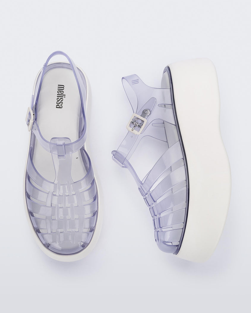 A top and side view of a pair of Clear/White Melissa Possession Platform sandals with several straps and a closed toe front.