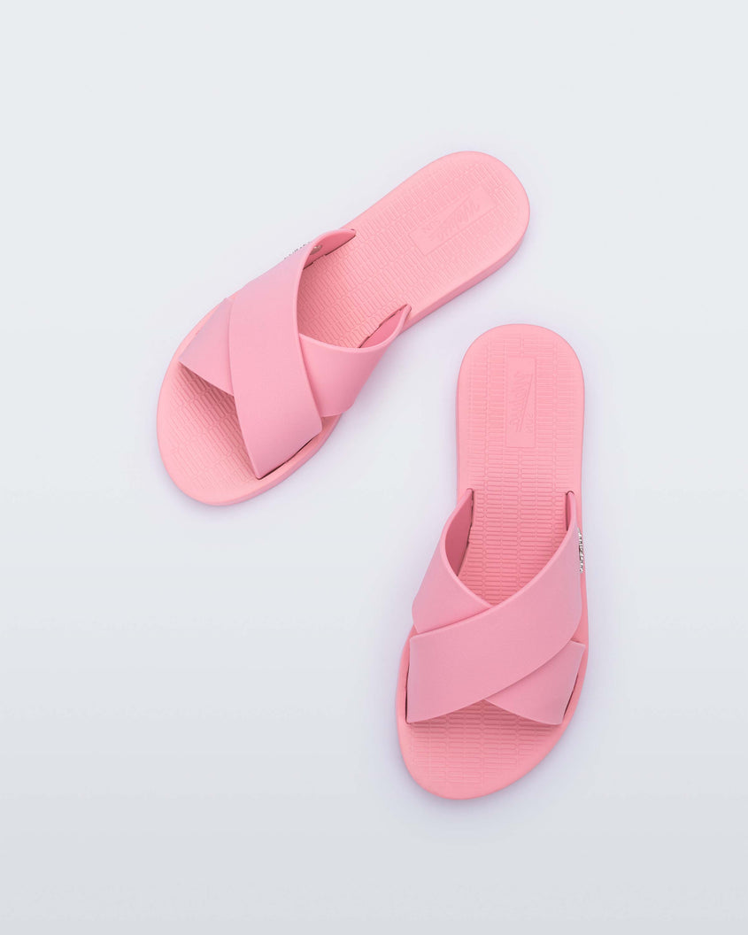 Top view of a pair of pink Melissa Sun City Walk slides with a melissa logo on the side and two overlapping straps.