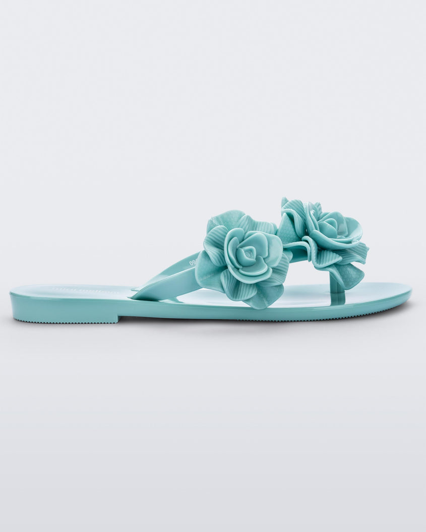 Side view of a green Melissa Harmomic Squared Garden flip flop with flowers on the straps.