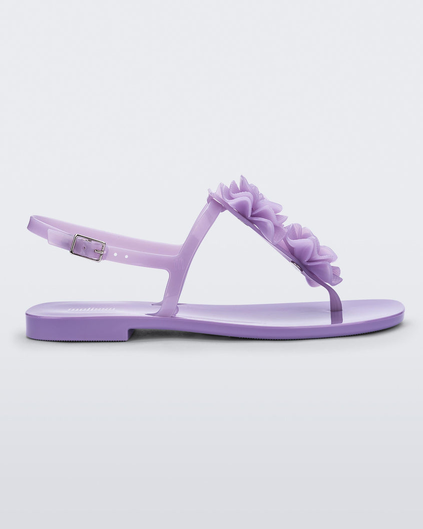Side view of a lilac Melissa Harmonic Squared Garden sandal with a flower decoration on the front strap.