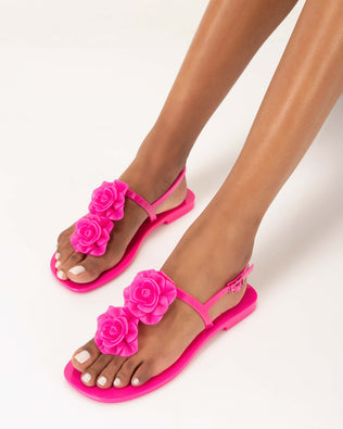 A model's legs wearing a pair of pink Melissa Harmonic Squared Garden sandal with a flower decoration on the front strap.