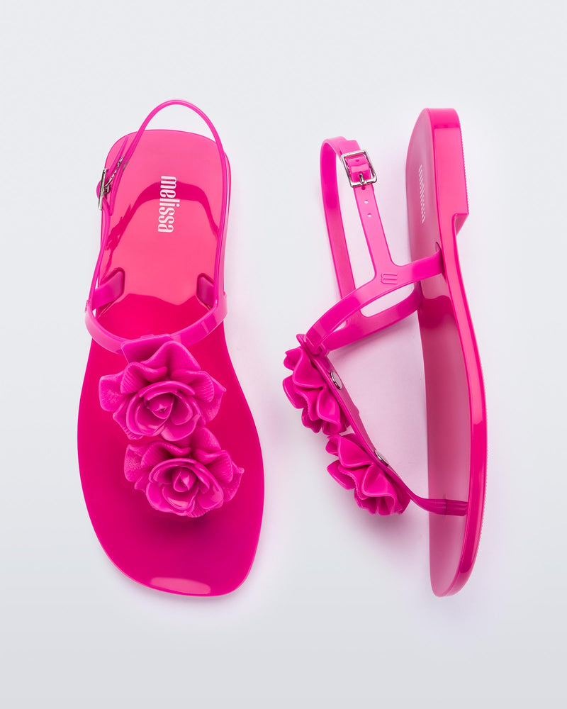 A top and side view of a pair of pink Melissa Harmonic Squared Garden sandals with flower decorations on the front straps.