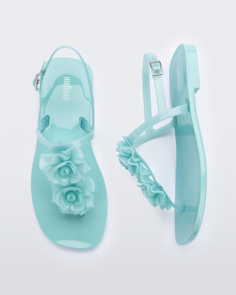 A top and side view of a pair of green Melissa Harmonic Squared Garden sandals with flower decorations on the front straps.