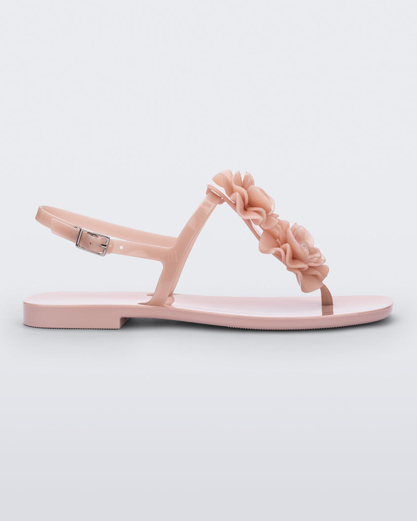 Side view of a light pink Melissa Harmonic Squared Garden sandal with a flower decoration on the front strap.
