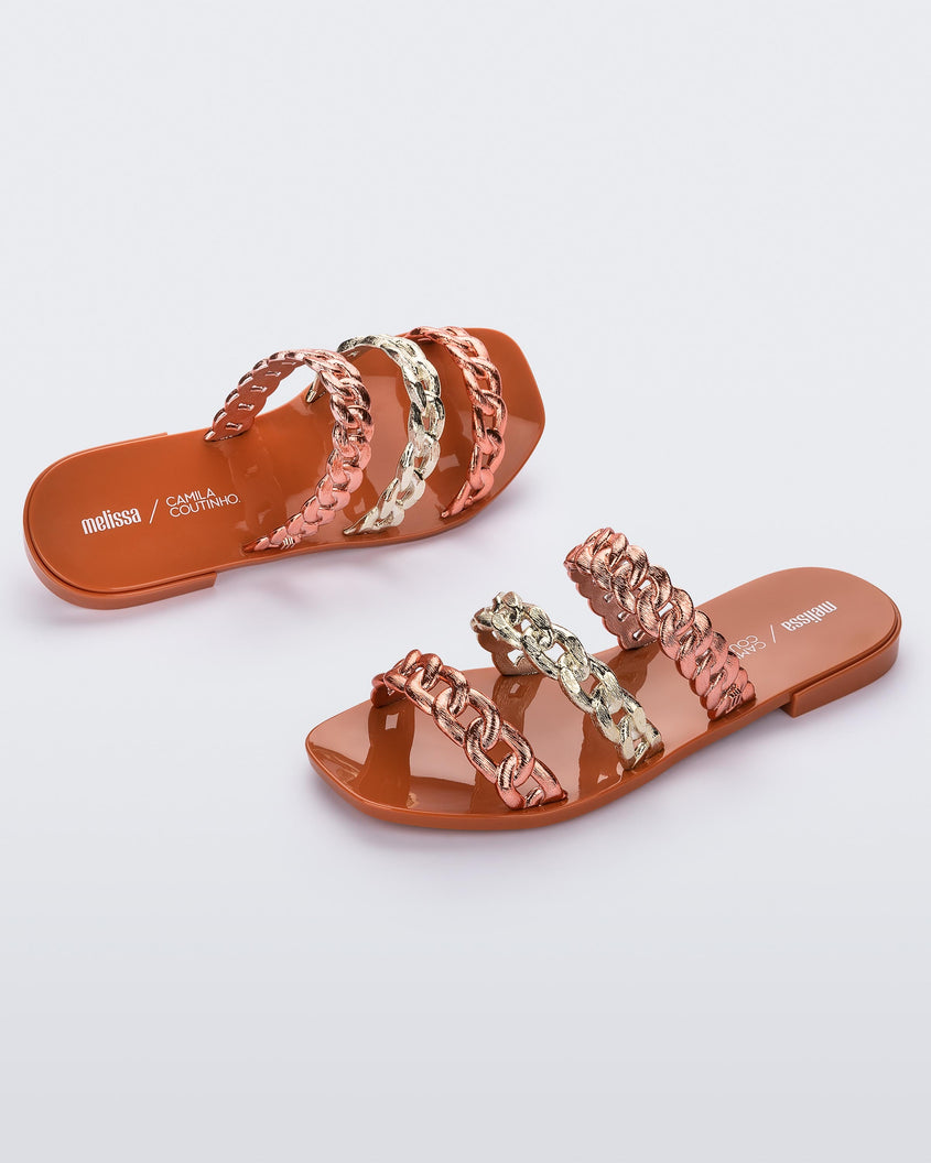 A top and side view of a pair of orange Melissa Feel slides three gold and orange chain detail straps.