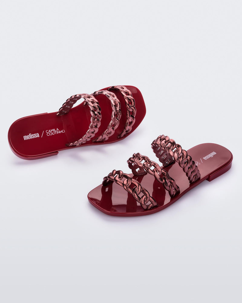 A top and side view of a pair of red Melissa Feel slides with three chain detail straps.