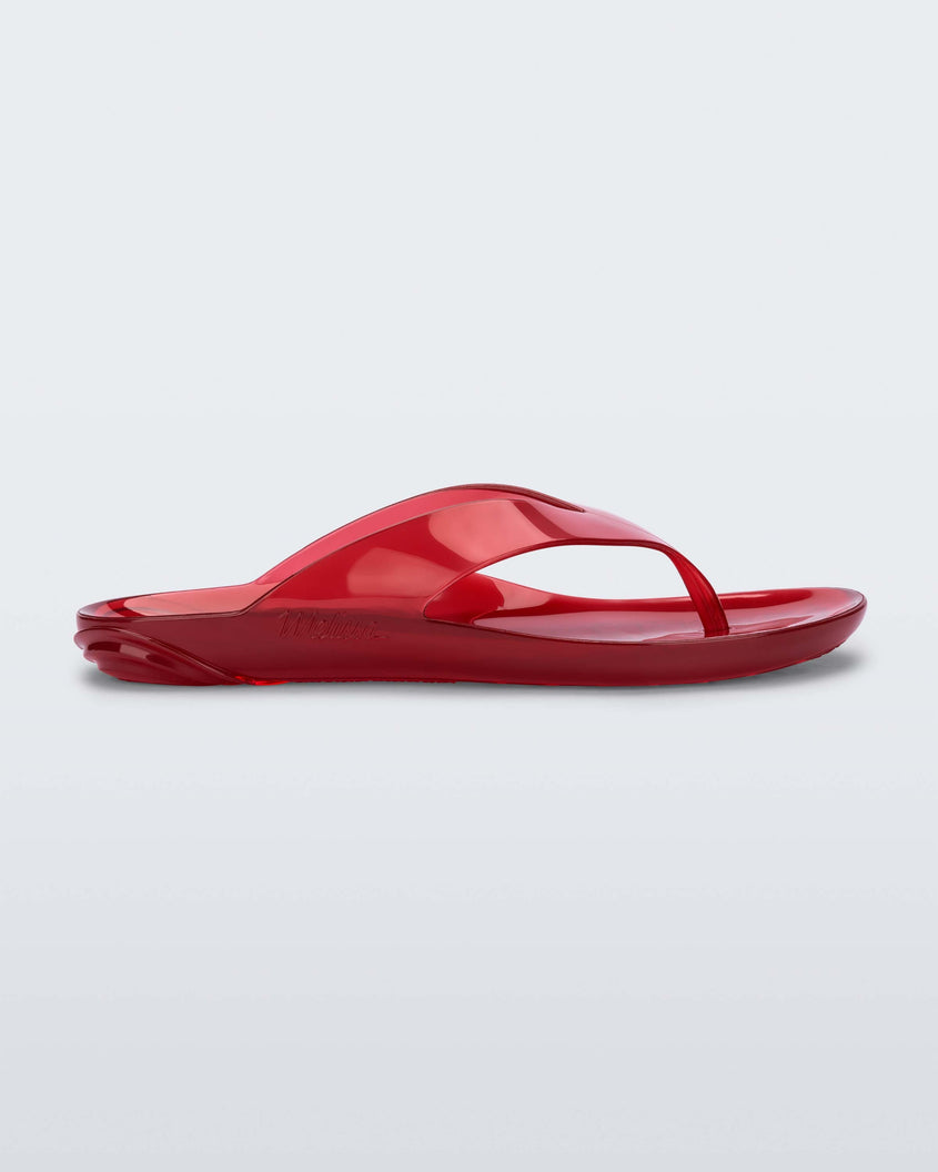 Side view of a clear red Melissa Real Jelly Flip Flop.