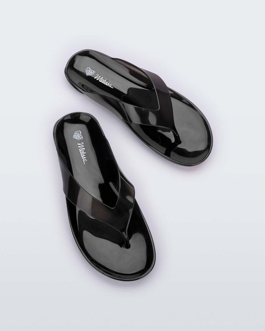 Top view of a pair of clear black Melissa Real Jelly Flip Flops.