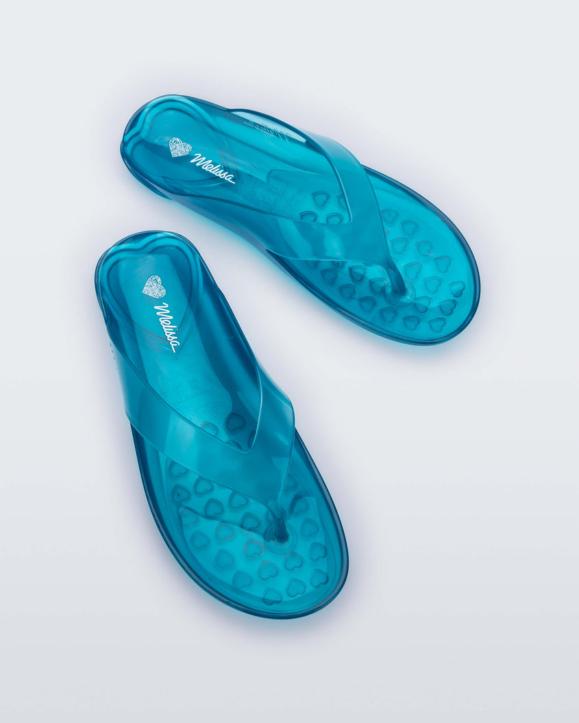 Top view of a pair of clear blue Melissa Real Jelly Flip Flops.