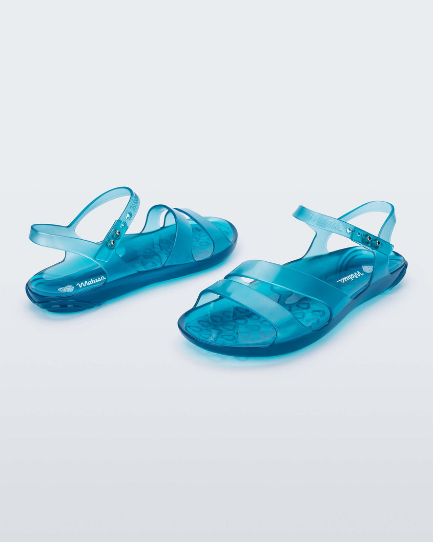 An angled front and side view of a pair of blue Melissa Real Jelly Sandals with two front straps and an ankle strap.