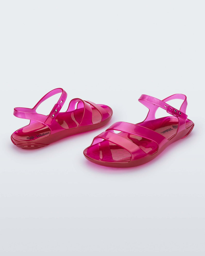 An angled front and side view of a pair of pink Melissa Real Jelly sandals with two front straps and an ankle strap.