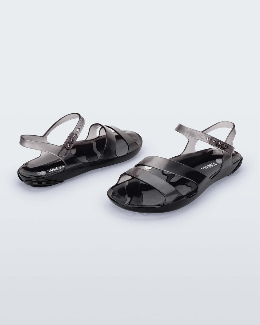 An inner and outter side view of a pair of black Melissa Real Jelly Sandals with two front straps and an ankle strap.