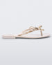 Side view of a beige Melissa Harmonic Stars flip flop with a bow and gold star details on the straps.