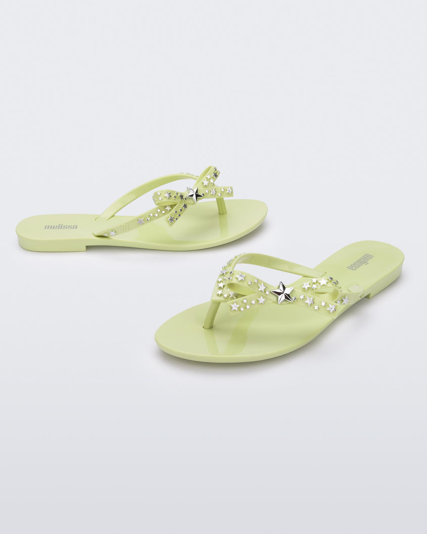 Angled view of a pair of green Melissa Harmonic Stars with a bow and silver star details on the straps.