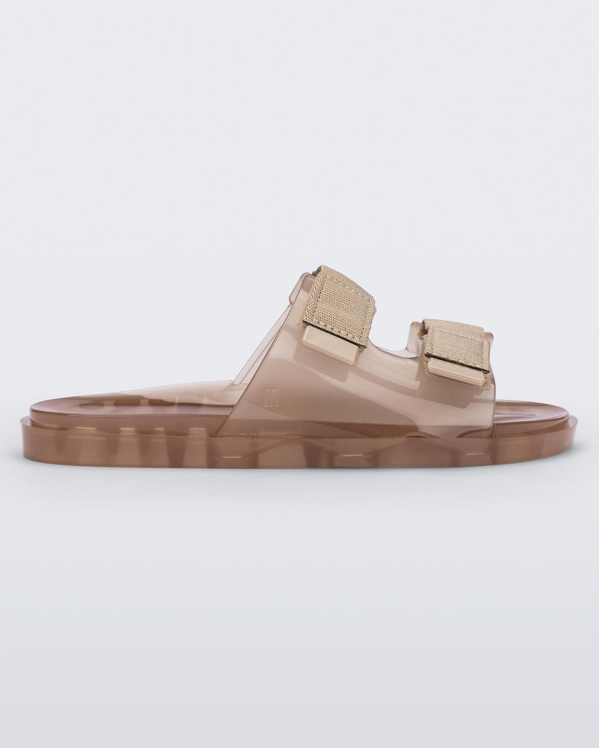 Side view of a brown Melissa Brave Wide slide with a brown base, velcro straps and a translucent brown insole.