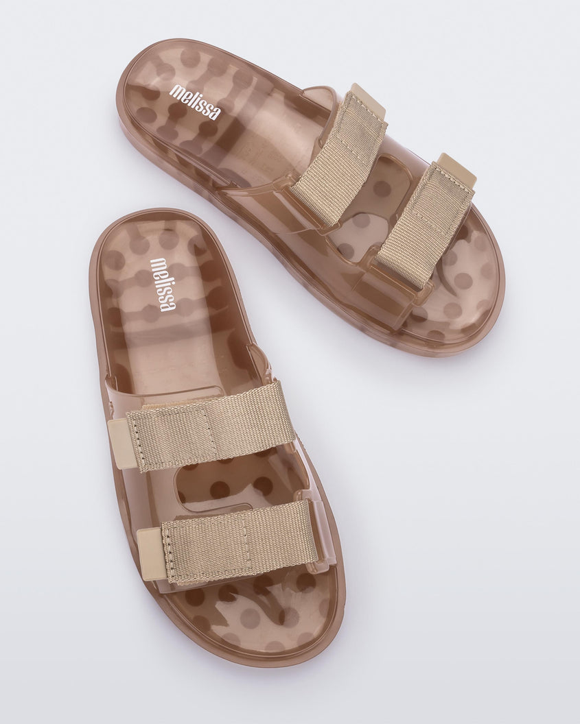 Top view of a pair of brown Melissa Brave Wide slides with a brown base, velcro straps and a translucent brown insole.