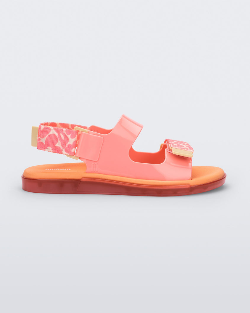 Side view of a pink Melissa Brave Papete sandals with an orange insole, pink flower print, pink straps and a velcro back.