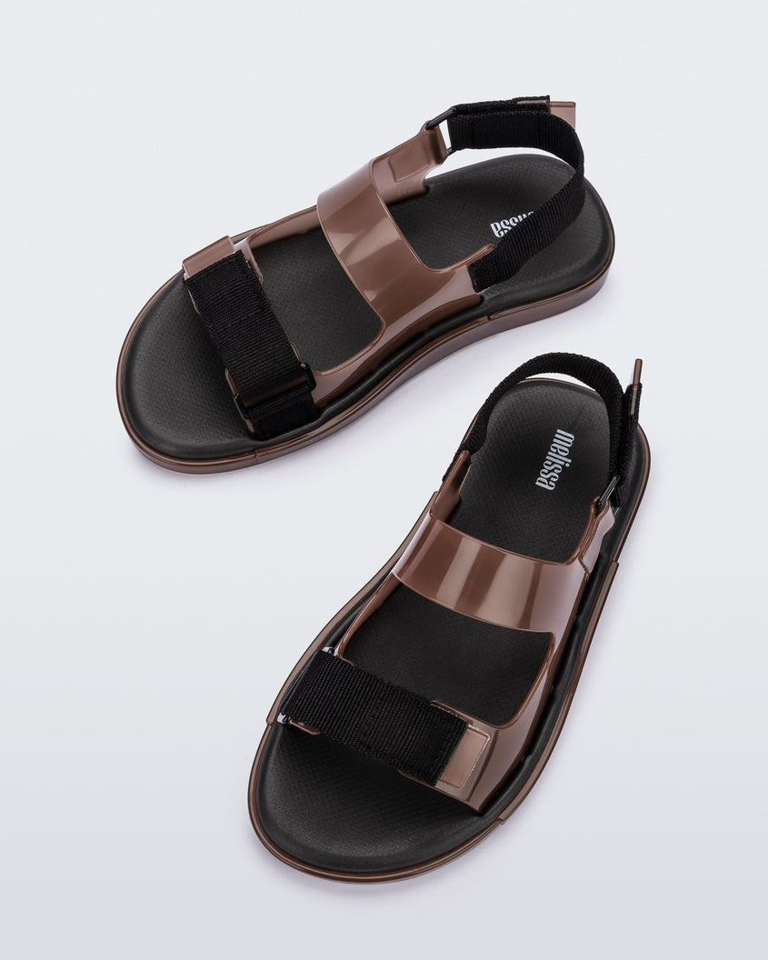 Top view of a pair of brown Melissa Brave Papete sandals with two straps, a brown base, black sole, and a front and back black velcro strap.