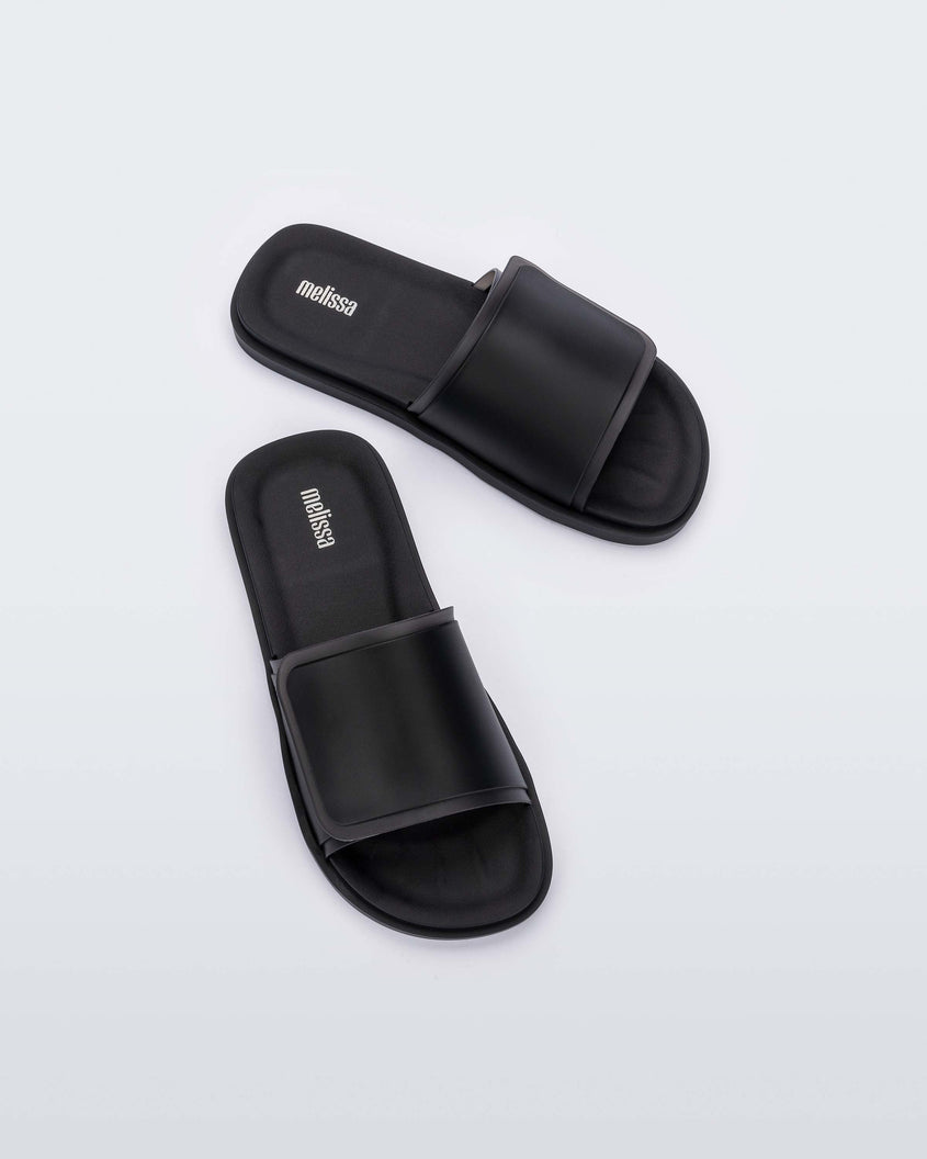 Top view of a pair of black Melissa Brave Slide with a black velcro top strap and black insole.