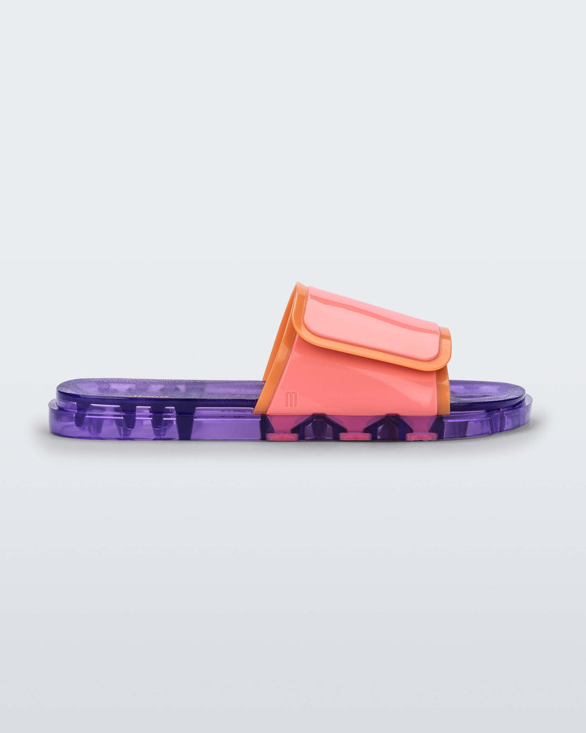 Side view of a lilac/pink Melissa Brave Slide with a pink and orange velcro top strap and translucent lilac insole.