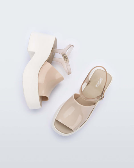A top and side view of a pair of White/Beige Melissa Pose platform sandals with a beige front strap, a clear beige ankle strap and a white sole.